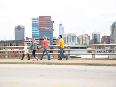 people walking across a bridge with a city in the background