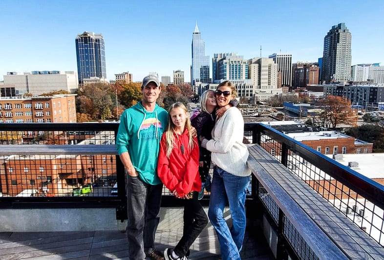 Warehousfamily on top of building with Raleigh skyline in the background in the Warehouse District, Raleigh, NC