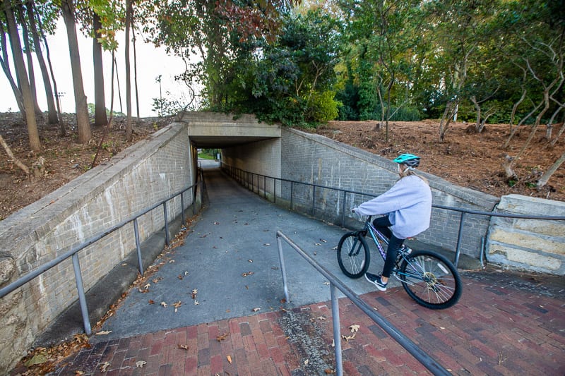 person riding a bike under a bridge