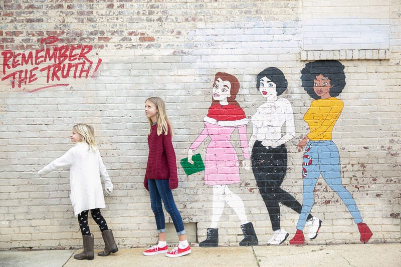girls standing next to a wall mural