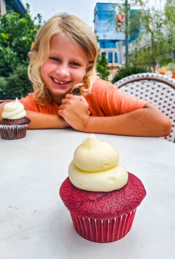 a girl sitting at a table with a cupcake