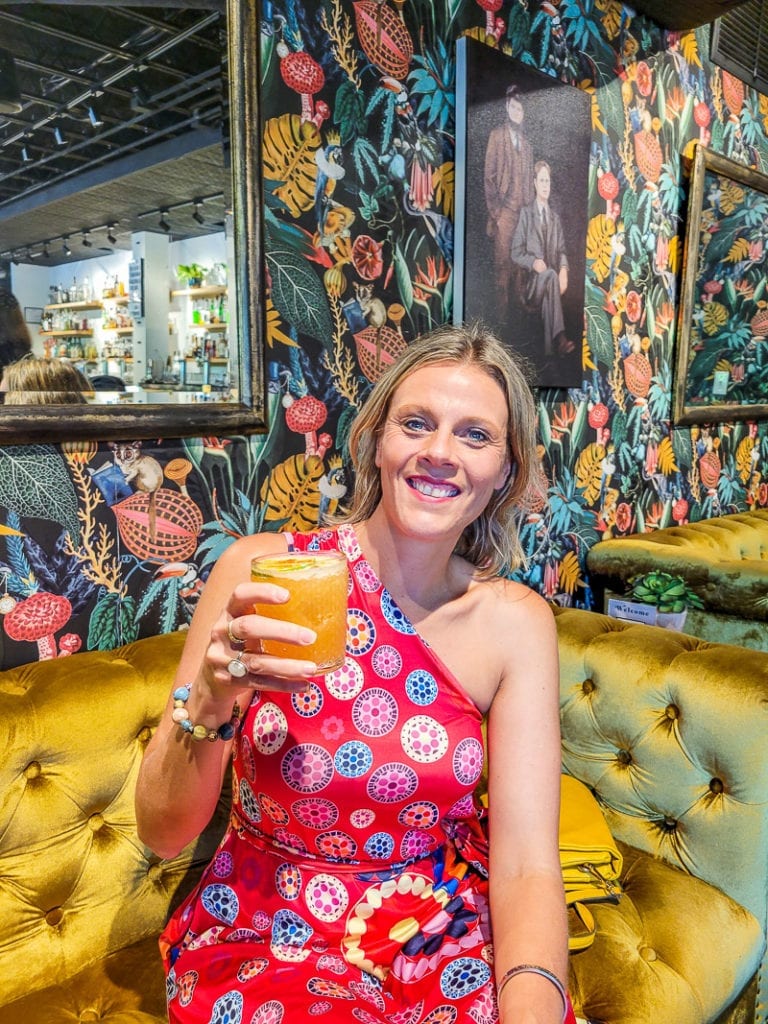 woman smiling for the camera while holding a drink