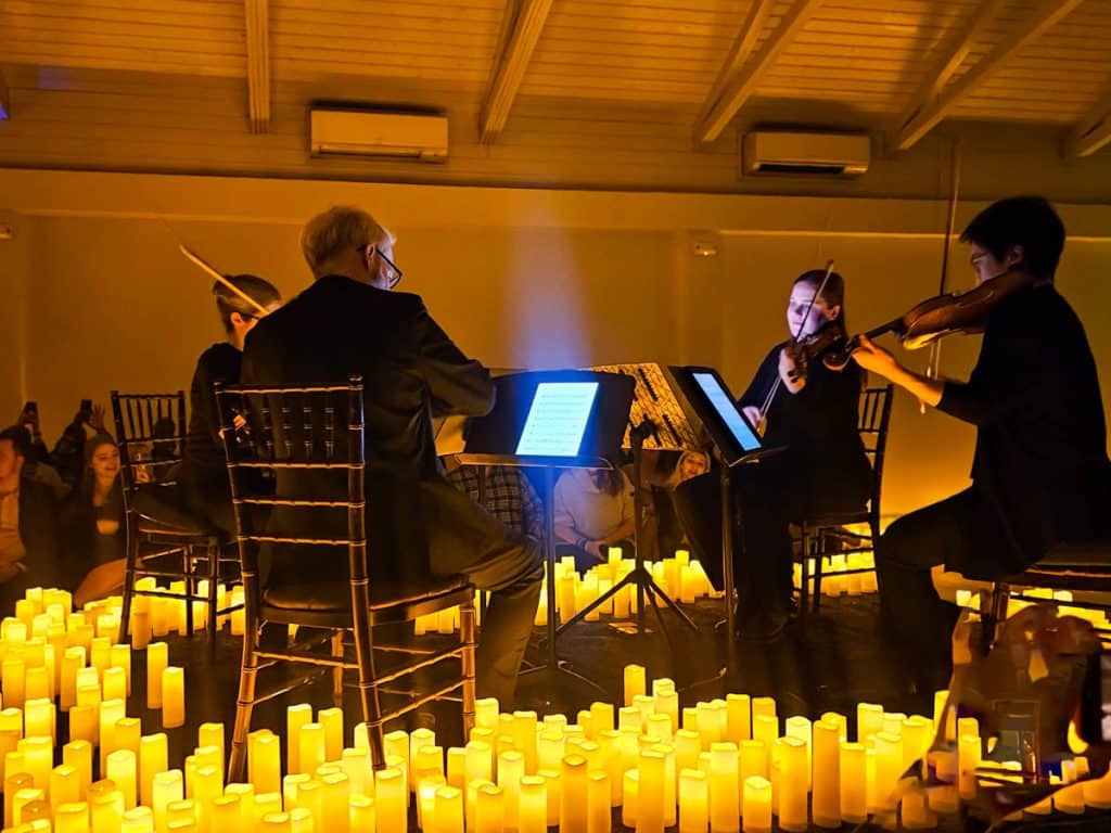 string quartet playing on small stage surrounded by candles