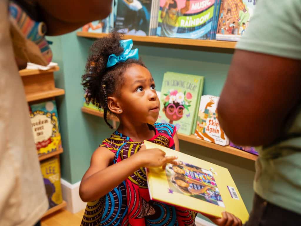 little girl holding book in bookstore