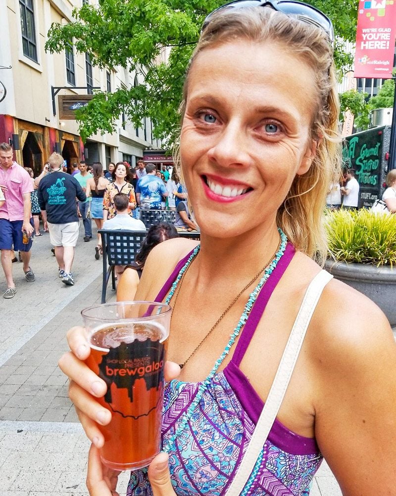 A woman smiling at the camera holding a glass of beer