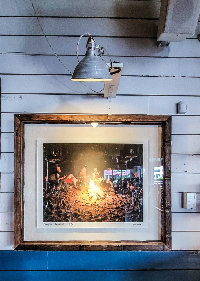 a framed photograph of people sitting around a beach bonfire