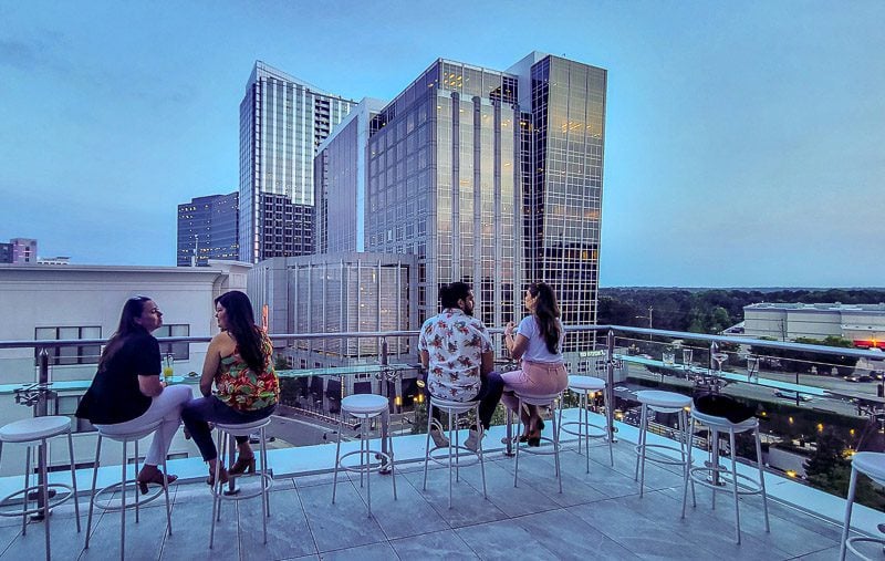 A group of people sitting on a rooftop patio looking at the views of buildings