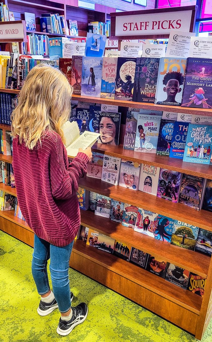 girl reading book inside Quail Ridge Books, North Hills
