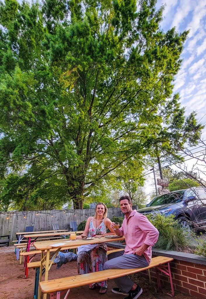 Couple having drinks outside under a gorgeous oak tree at The Stanbury, Raleigh