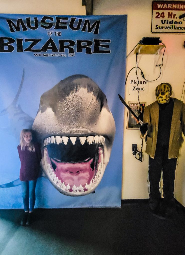 Child standing next to a shark poster at a museum
