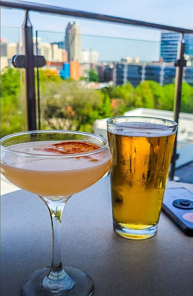 Cocktail and beer on a table with city views behind