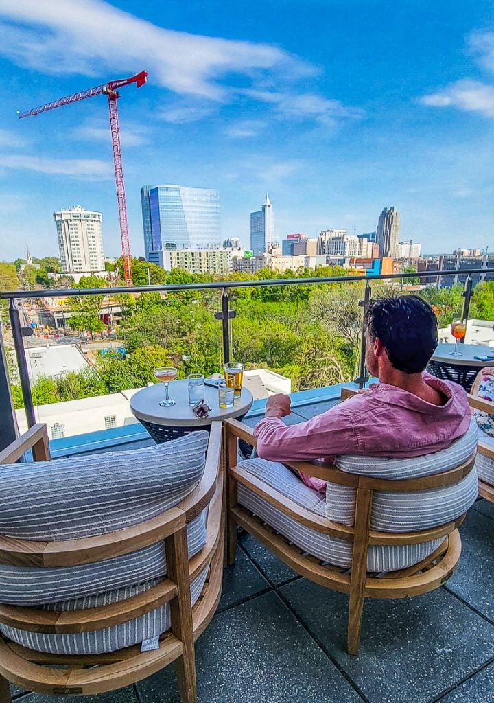 Man having a drink at a rooftop bar with city views