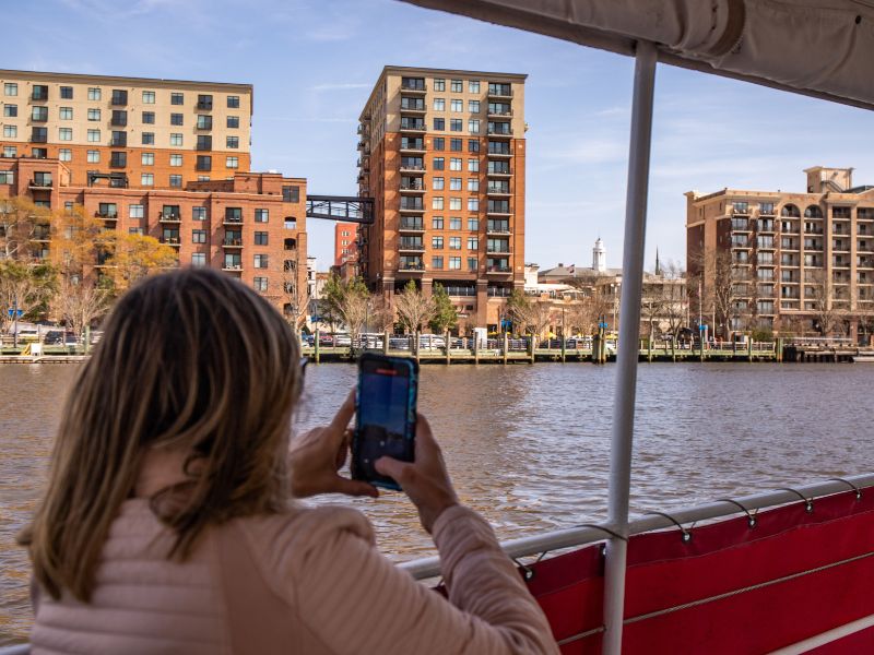 Lady taking a photo of the river and buildings in background