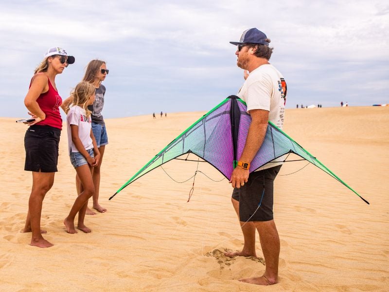 Man holdinga kite while talking to three ladies in the sand dunes - Outer Banks