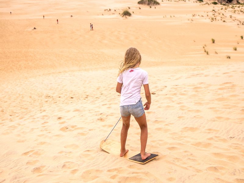 Girl sand boarding down a sand dune - Outer Banks