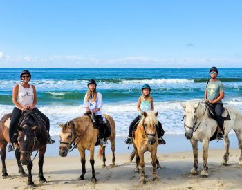 Family of four horse riding on the beach in the Outer Banks
