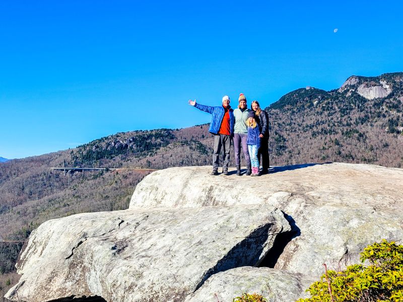 Family of four posing for a photo on a rock in the mountains