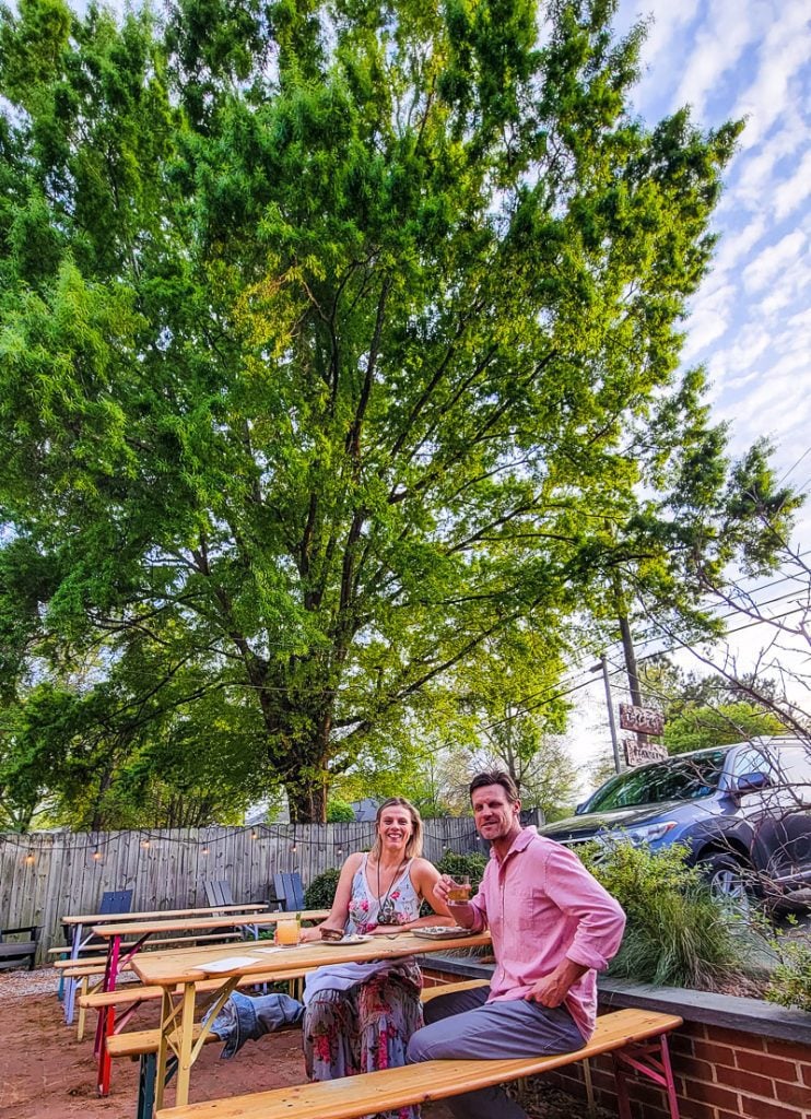 Couple sitting at a table under an oak tree having drinks at the Stanbury Restaurant
