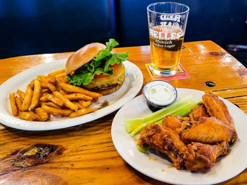 Plates of burgers, fries and wings in a bar
