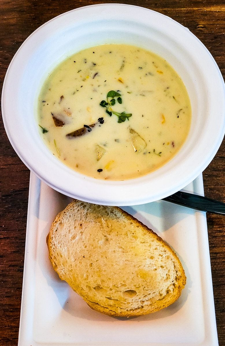 a bowl of corn chowder and slice of bread