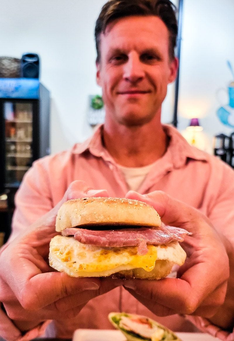 man holding a bacon and egg biscuit