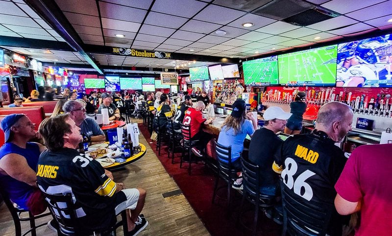Sports fans watching a game in a sports bar sitting at tables and the bar