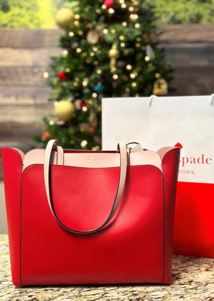 red kate spade purse in front of tree