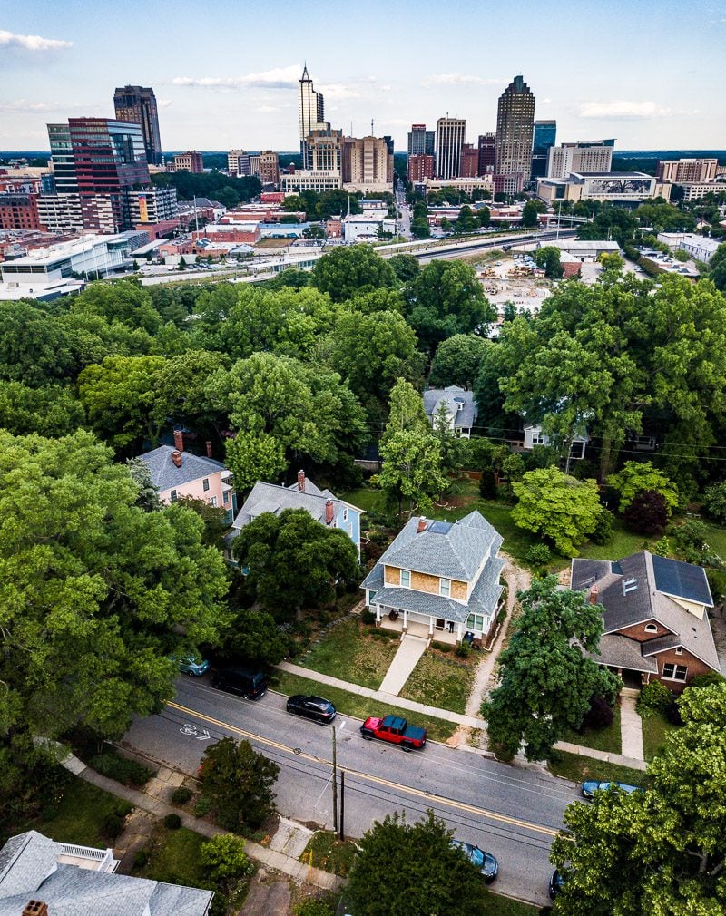 Aerial view of a home surrounded by trees and city skyline in the background