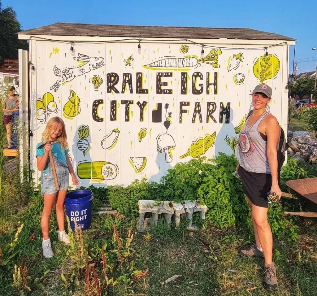 two people standing in front of Raleigh city farm sign