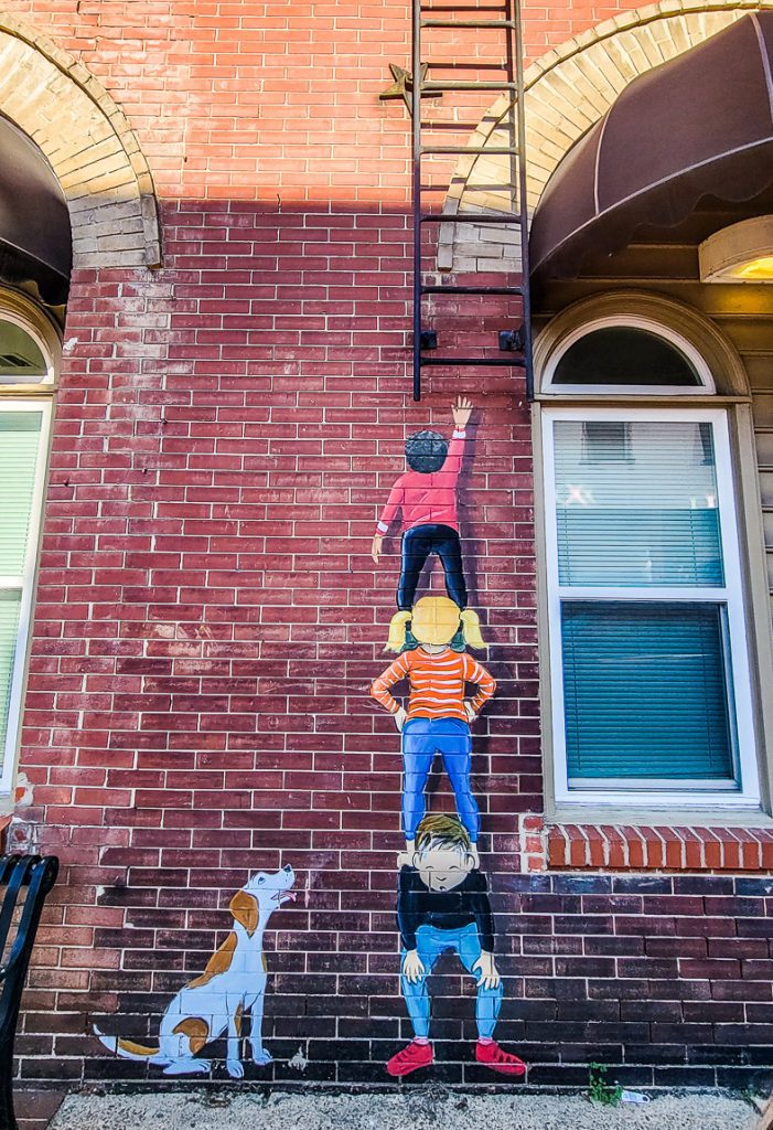 Mural of kids climbing a ladder up a wall