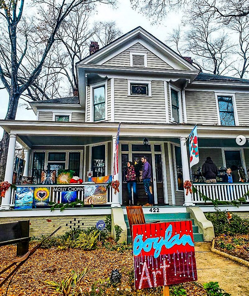 People shopping for artwork on the front porch of a home in a neighborhood