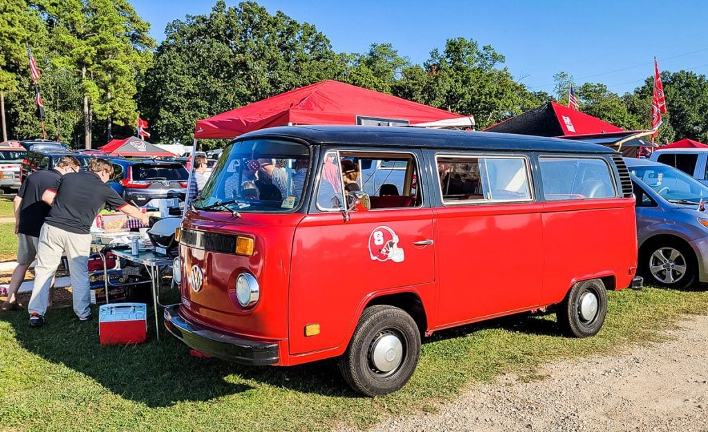 Red Volkswagen van and football fans tailgating