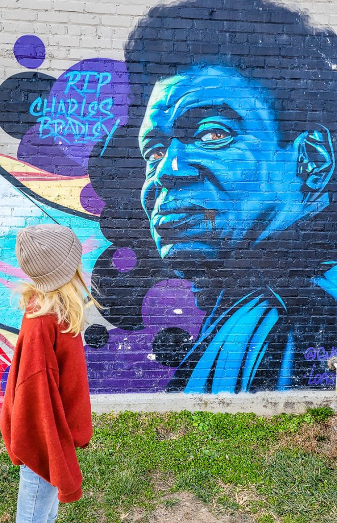 Girl looking up at a mural of a black man