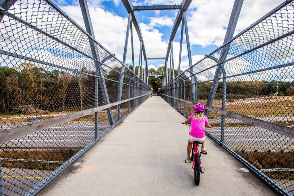Young girl riding her bike across a bridge