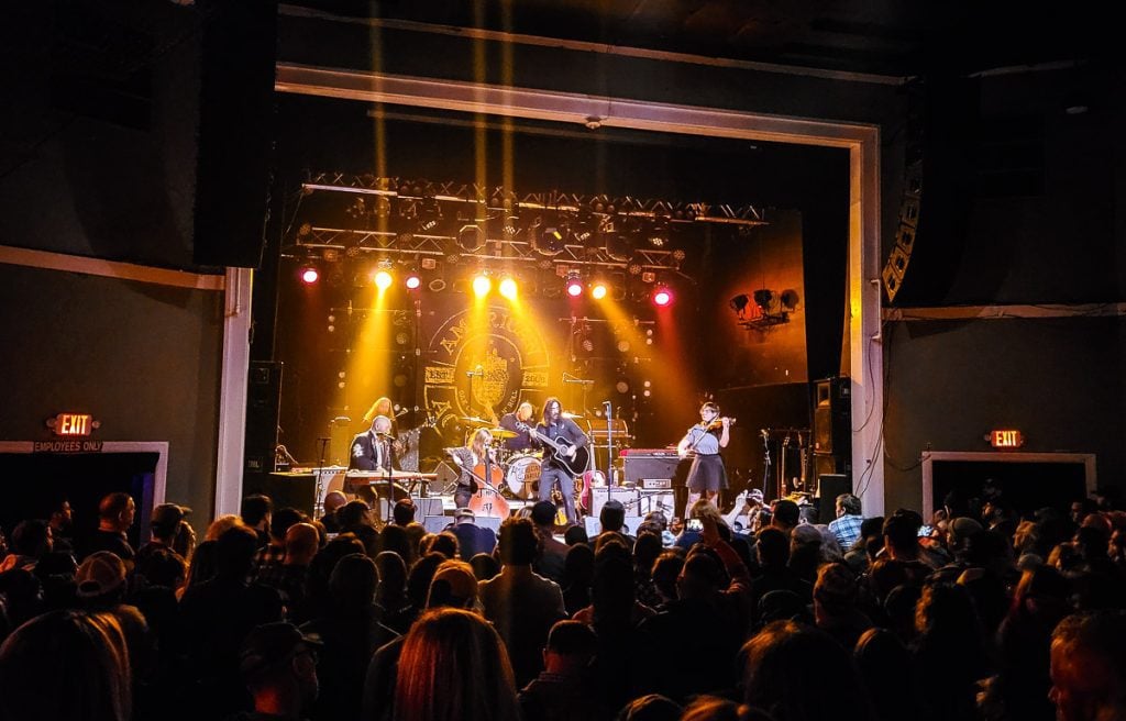 Band playing on stage to a crowd at an indoor concert venue