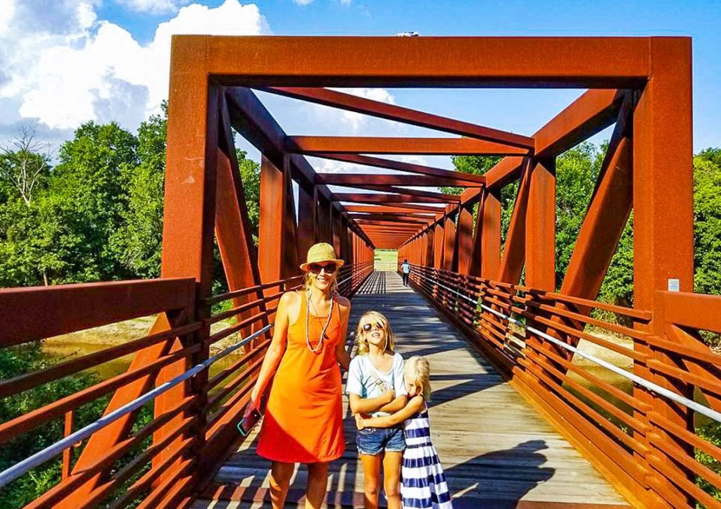 Mother and two daughters walking across a bridge on a trail
