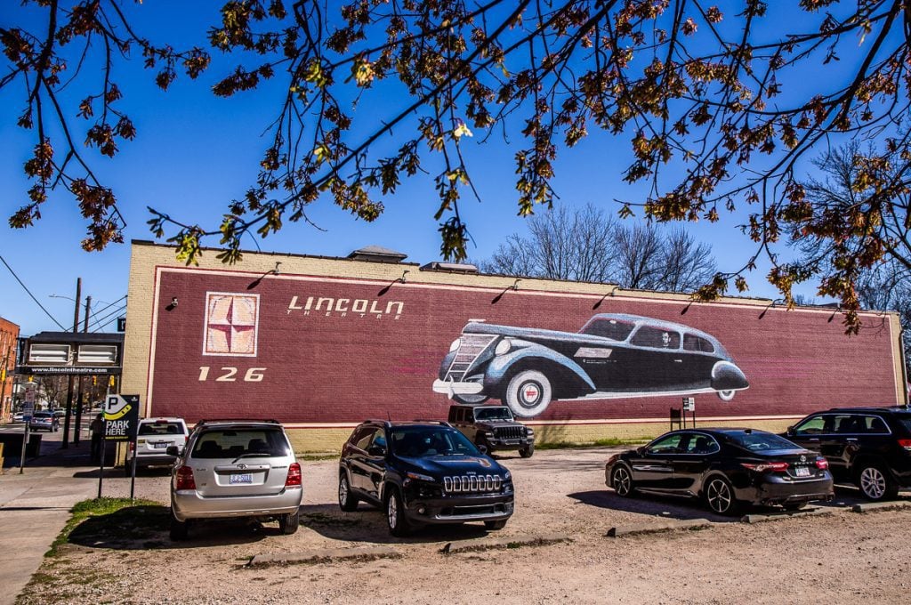 Mural of a Lincoln car on the side of a music venue called The Lincoln Theatre