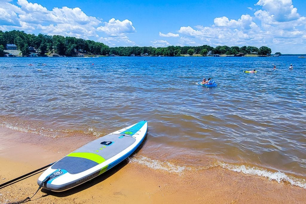 Paddle board at the edge of a lake and people swimming