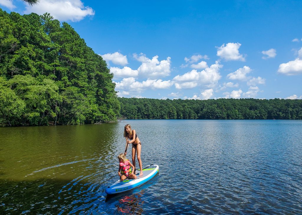 Two girls paddling on a paddle board on a lake