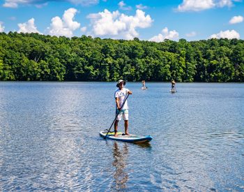 Man paddling a paddle board on a lake surrounded by forest
