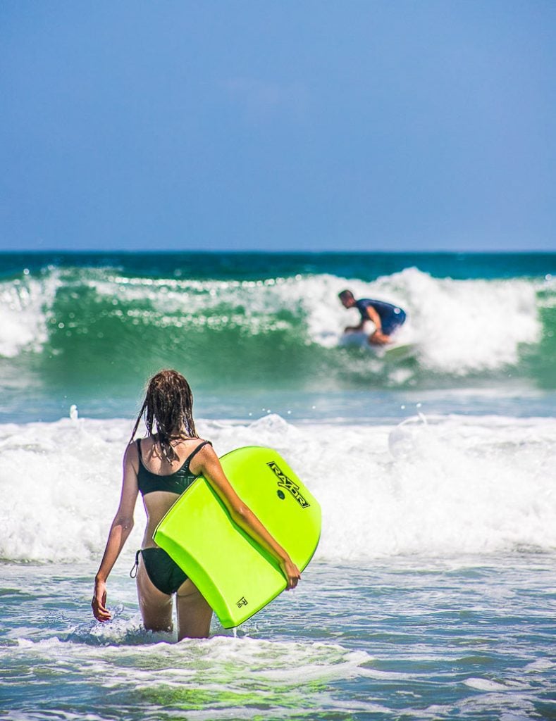 Young girl at the beach holding a body board