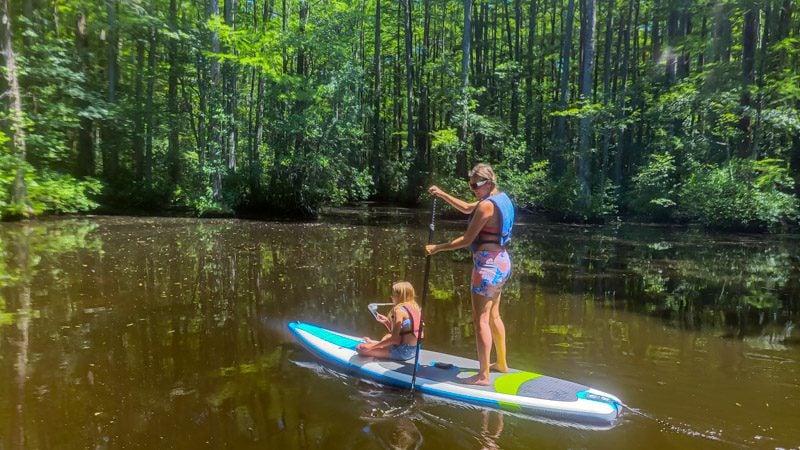 woman paddling sup board with child on front