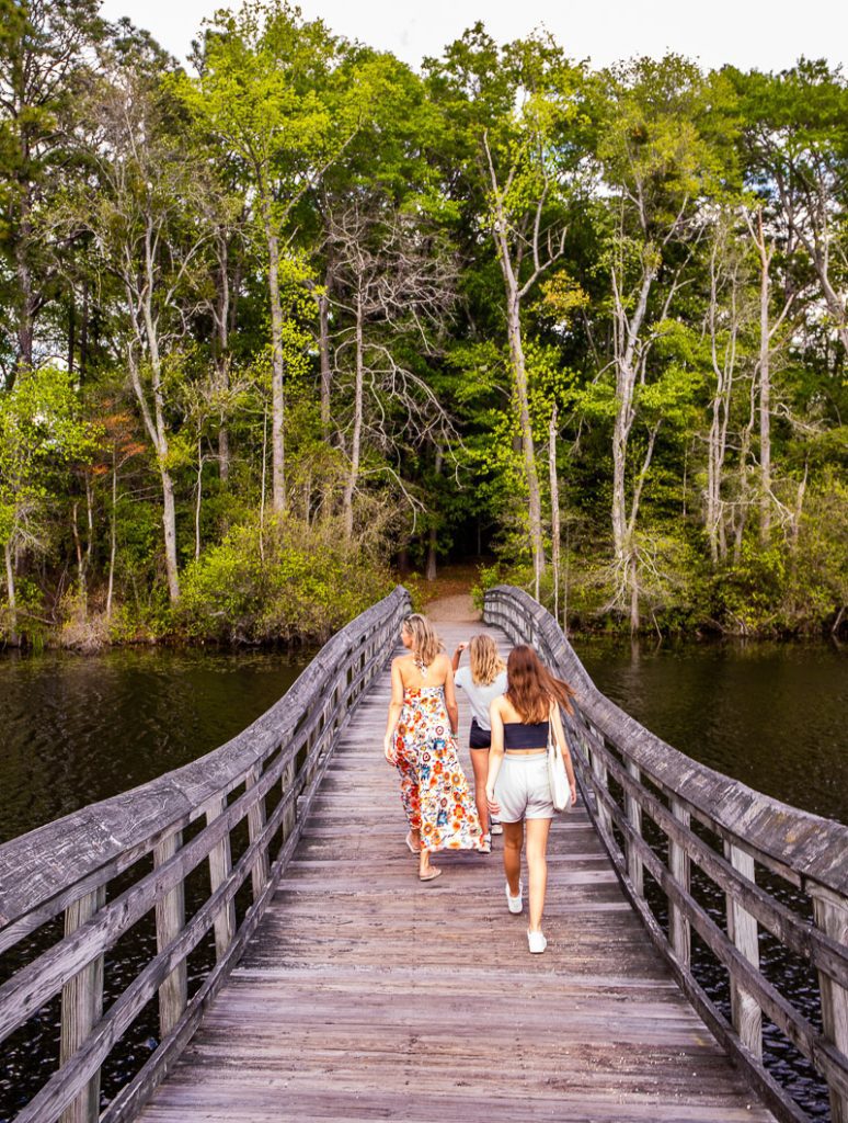 Mom and daughters walking across a bridge over a lake