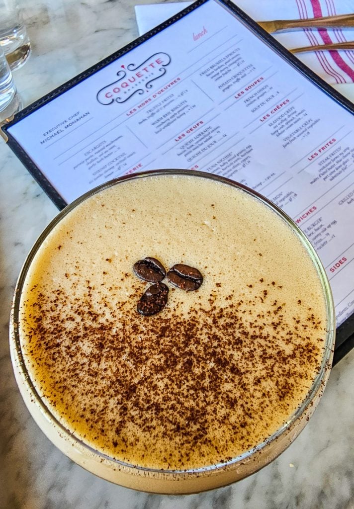Espresso Martini on a table with a menu behind it.