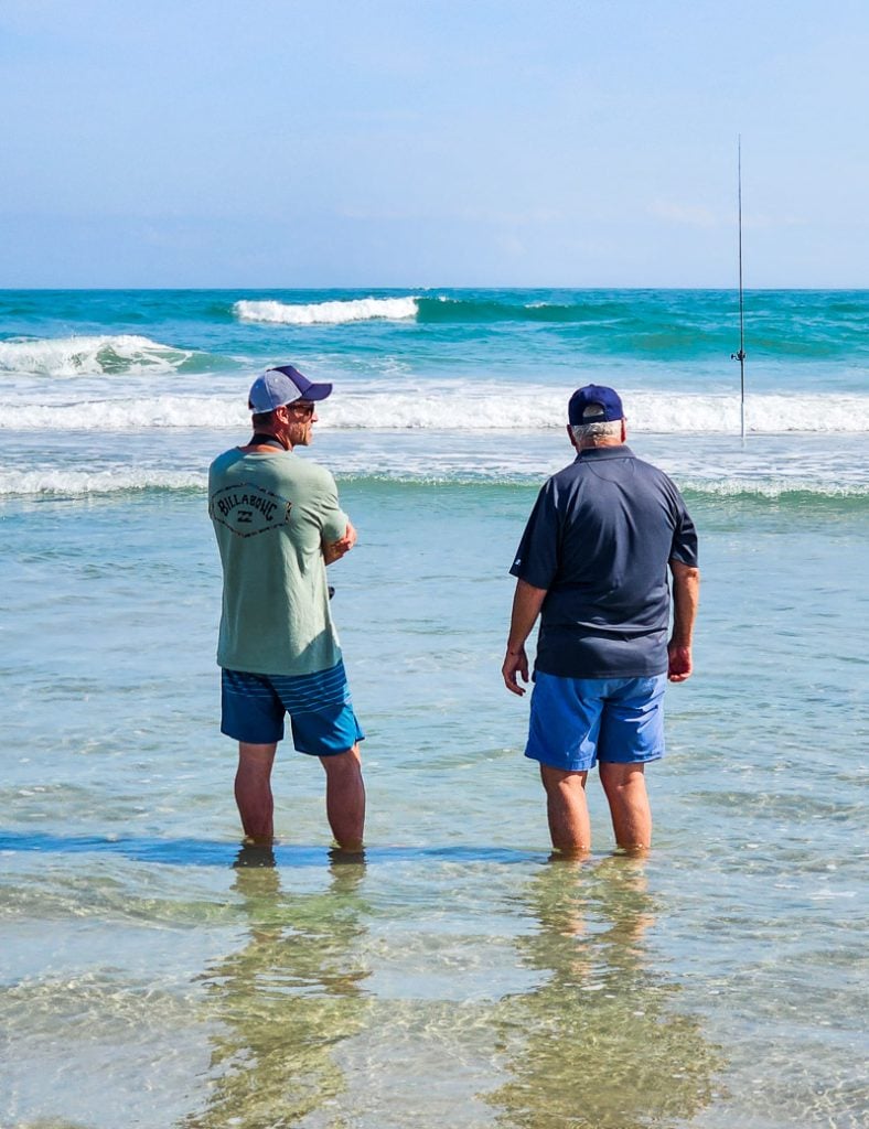 Two men standing in the ocean chatting