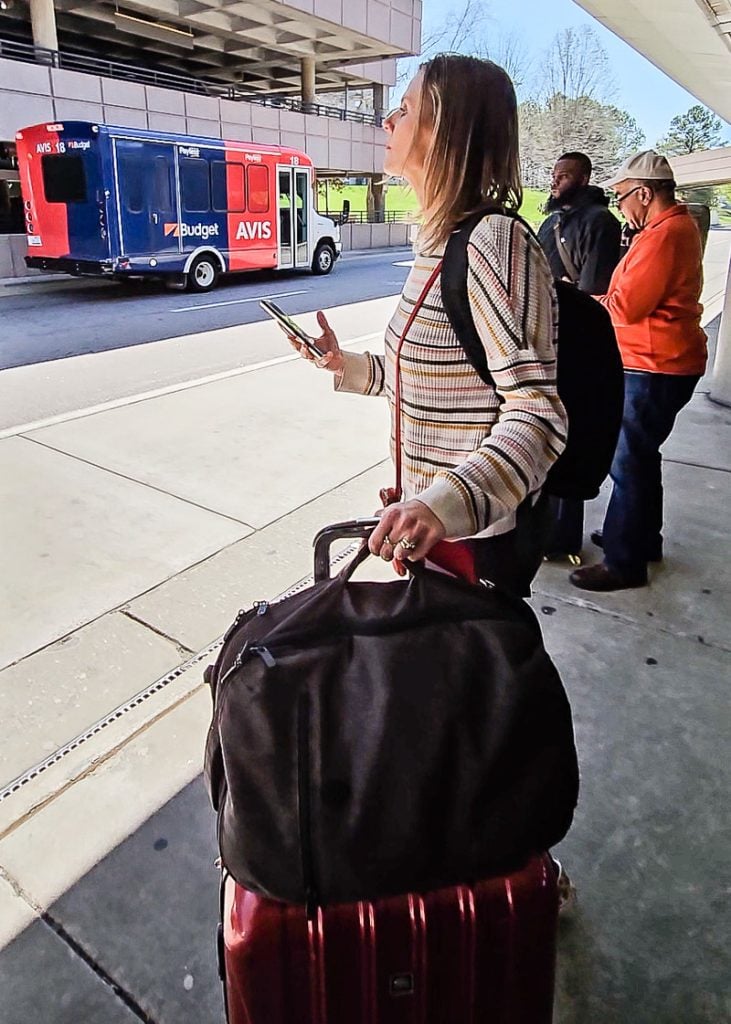 Lady standing with travel luggage waiting for an UBER