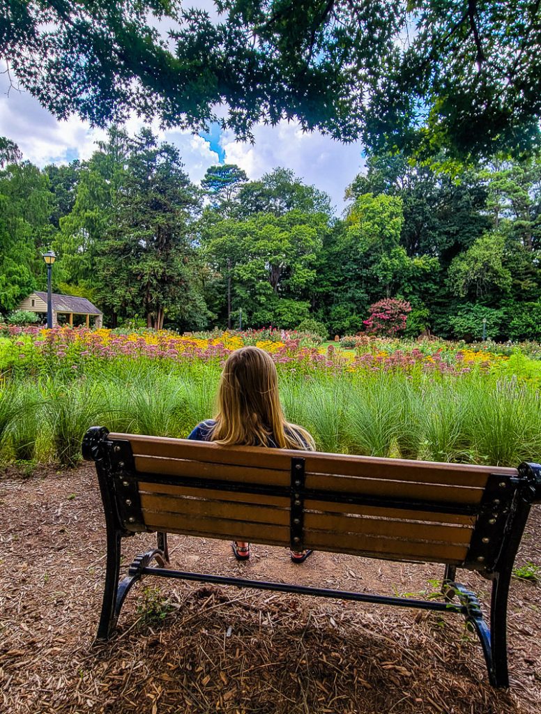 Girl sitting on a wooden seat in a garden