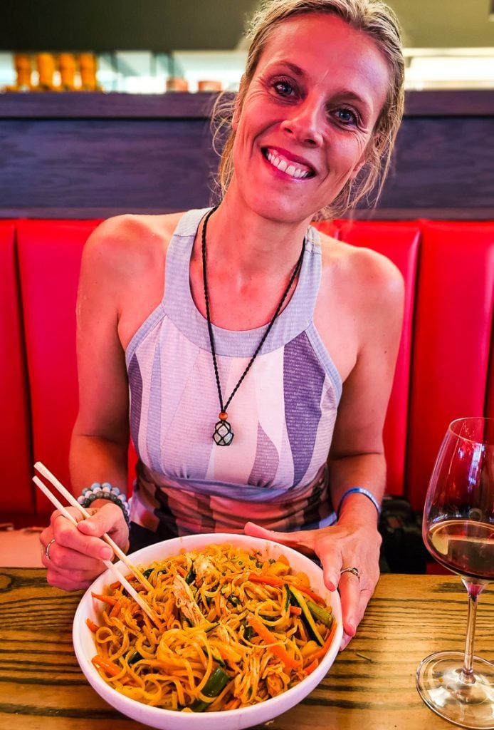 Lady eating a bowl of noodles in a restaurant
