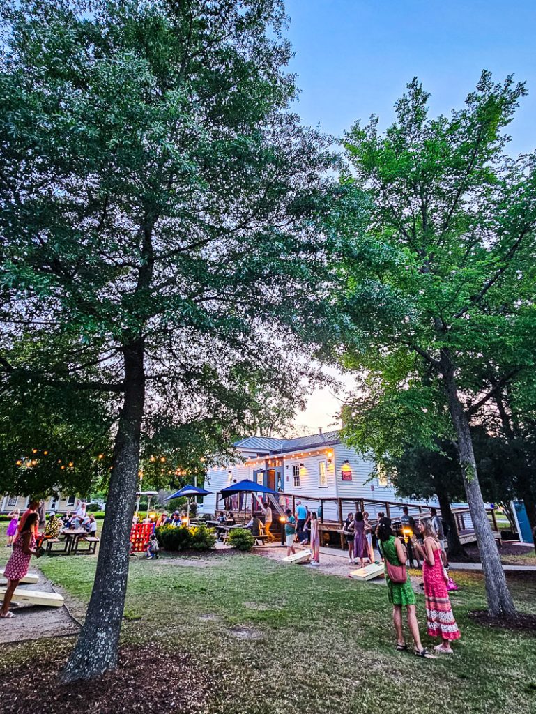 People outside in a beer garden surrounded by trees