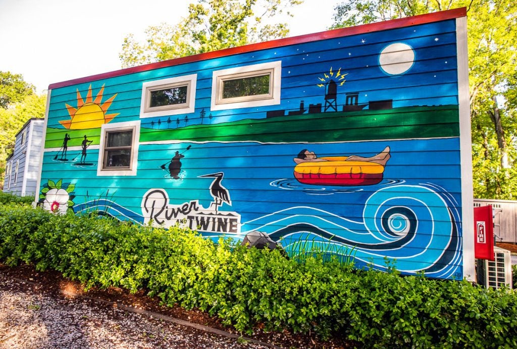 A colorful tiny home with a mural saying River and Twine